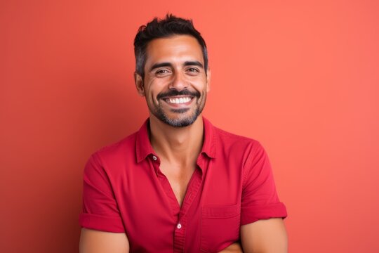 Portrait of a happy young indian man smiling on red background