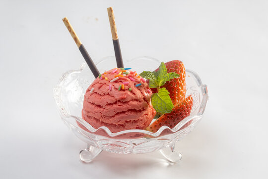 Strawberry ice cream in a white bowl with strawberries, napkins on a wooden boards background