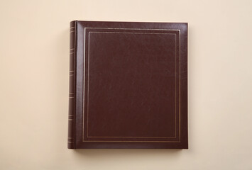 Photo album with leather cover on beige background, top view