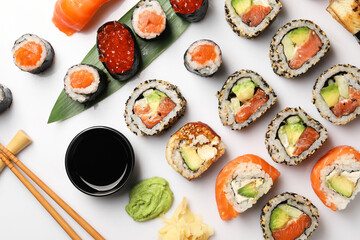 Set of delicious sushi rolls on white background, flat lay