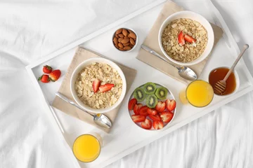 Foto op Plexiglas Tasty breakfast served in bed. Oatmeal, juice, fruits, almonds and honey on tray, top view © New Africa