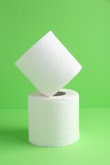 Soft toilet paper rolls on green background, closeup