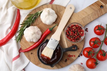 Marinade in gravy boat, ingredients and basting brush on white table, flat lay