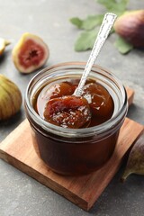 Jar of tasty sweet fig jam on grey table