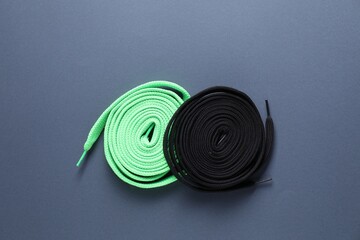 Stylish black and green shoe laces on grey background, top view