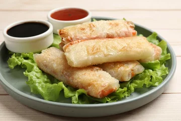 Foto op Plexiglas Delicious fried spring rolls and sauces on light wooden table, closeup © New Africa