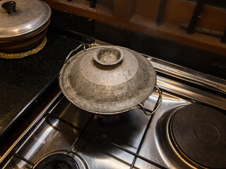 Round bottom frying pan with stir fry of shrimp on gas burner of stove with warm white overhead lighting