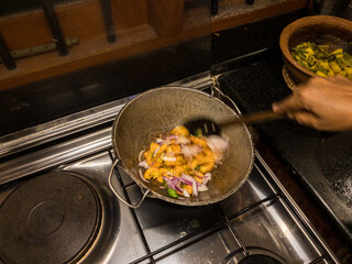 Stirring and cooking Round bottom frying pan with stir fry of shrimp on gas burner of stove with warm white overhead lighting