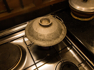 Covered Round bottom frying pan with stir fry of shrimp on gas burner of stove with warm white overhead lighting