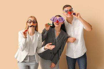 Business people in funny disguise with party whistles on beige background. April Fools' Day...