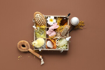 Brushes and cosmetics for spa procedures, flowers with Easter decor on brown background