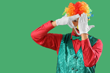 Portrait of playful clown on green background. April Fool's day celebration