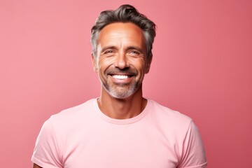 Portrait of a handsome mature man smiling at camera against pink background - obrazy, fototapety, plakaty