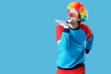 Portrait of clown blowing kiss on blue background. April Fool's day celebration