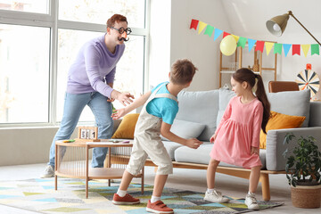 Father in funny disguise playing with his children at home. April Fool's Day prank