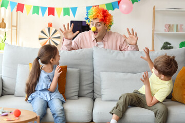 Father in colorful clown wig surprising his children at home. April Fool's Day prank