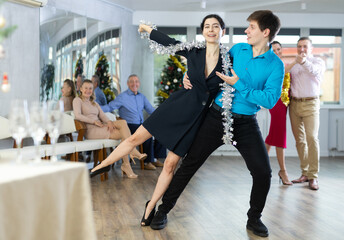 Christmas holiday - men and women in festive clothes with tinsel dancing slow ballroom dance during...