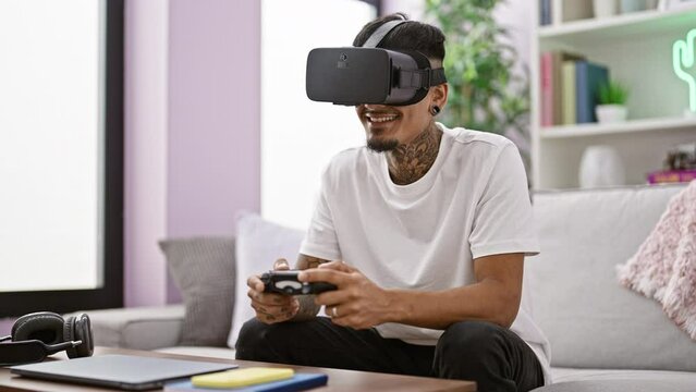 Confident young latin gamer happily using a joystick and vr glasses while playing intense video games in his comfortable living room