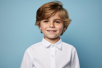 Portrait of a smiling little boy in a white shirt on a blue background