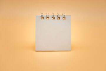 Blank calendar isolated on orange background. Blank paper desk spiral calendar. close up of a blank recycle paper template.