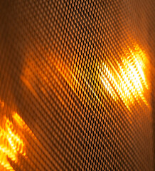 abstract background of a metal grid with a glowing orange light.