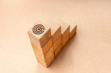 Target dart icon on top of wooden blocks graph steps on brown kraft paper background, top view....