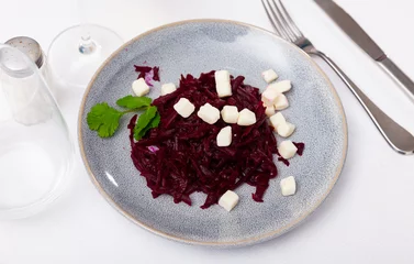 Fotobehang Healthy and easy-to-prepare appetizer for meat dishes is salad of stewed grated beetroot, seasoned with cheese cubes, and garnished with coriander sprigs. © JackF