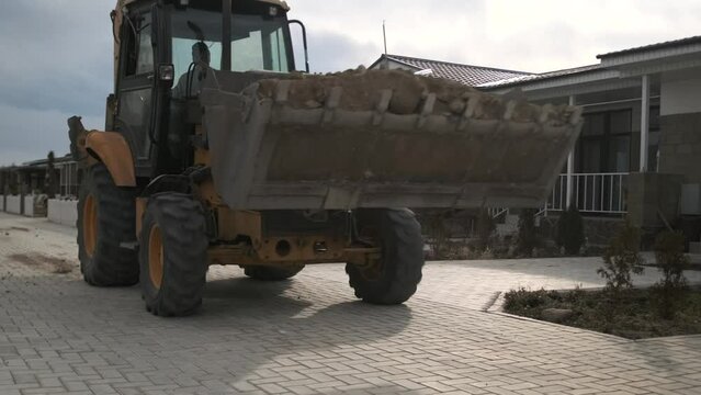 Wheel loader. Backhoe loader driving along the street of suburban village to carry out construction work on a new facility. Close up. Construction equipment.