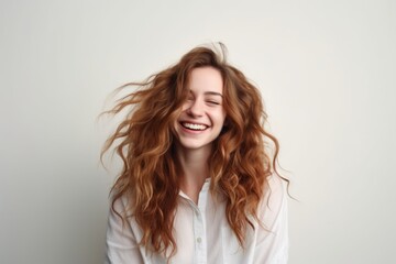 Portrait of a happy young woman with long red hair smiling and laughing.