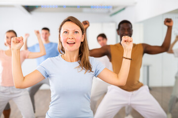 Cheerful energetic multiracial dancers of different ages dancing aerobics at lesson in modern class...