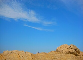 Two people on the rocks of cliffs landscape with blue sky background