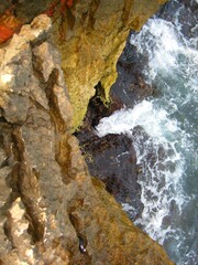 Waves crashing on seashore rocks, Top view sea surface waves background