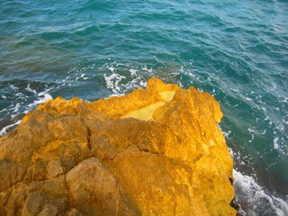 Waves crashing on seashore rocks, Top view sea surface waves background