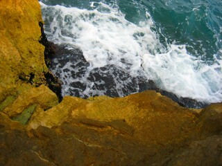 Waves crashing on seashore rocks, Top view sea surface waves background