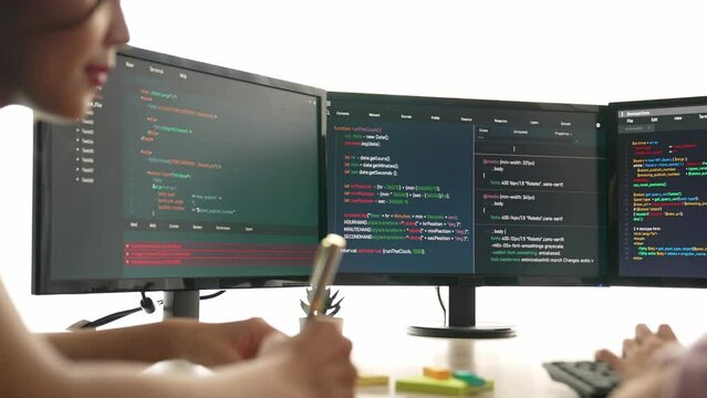 Slow motion back end software developer engineer for computer programming working together on debugging writing computing code, solving complex algorithms display on monitor in office. Burgeoning