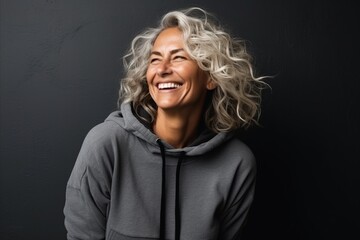 Portrait of a beautiful middle aged woman laughing against a dark background