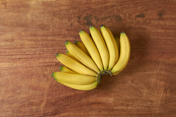 bunch of fresh bananas on a wooden table top, harvested ripe tropical fruit with bright yellow peel and deliciously sweet flavor, taken straight from above with copy space - Powered by Adobe