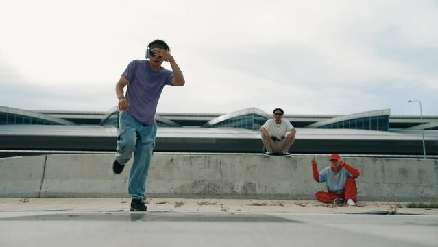 Group of asian break dancer perform street dance with multicultural friend support and moving hip hop music. Attractive handsome hipster practice b boy dance at street. Outdoor sport 2024. Sprightly.