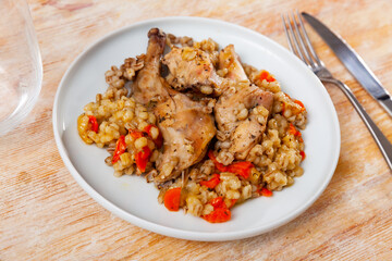 Fototapeta premium Traditional pearl barley porridge with stewed vegetables and fried rabbit on a plate