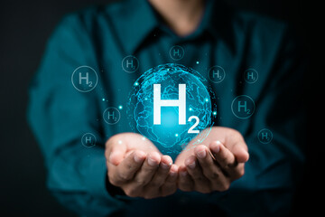 Clean hydrogen energy concept. Businessman holding globe with H2 icon on virtual screen for...