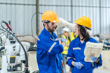 woman engineer in uniform helmet inspection check control heavy machine robot arm construction installation in industrial factory. technician worker check for repair maintenance electronic operation