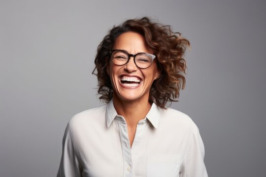 Portrait of a happy businesswoman laughing at the camera while standing against grey background