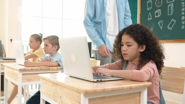 Caucasian teacher helping american student coding engineering prompt while diverse student using software generated AI. Smart attractive children sitting and programing system. Education. Pedagogy.