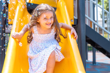 Happy girl playing in playground surrounded by soap bubbles