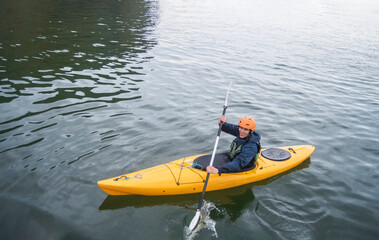 Yellow kayak. It is a man in a yellow kayak. He is rowwing and smiling.