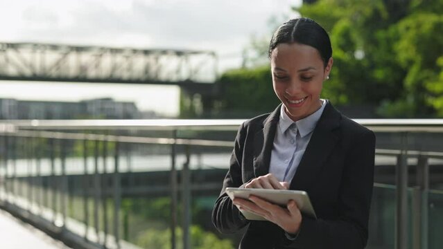 Positive Adorable Girl Using the Digital Tablet Outside while Standing at the Street and Scrolling the Internet. Cute Happy Businesswoman Outdoors with Device Distance Working. People and Technology