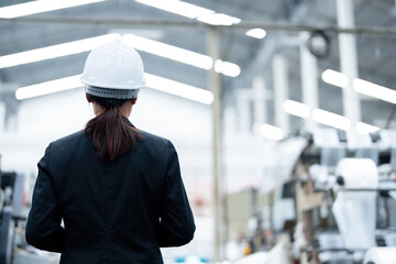 Back view of an Asian female engineer and company owner standing in a car manufacturing plant...