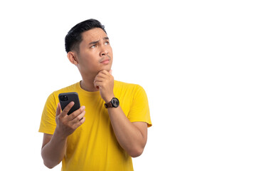 Pensive handsome Asian man holding mobile phone, touching his chin, looking at copy space, thinking about online offer isolated on white background