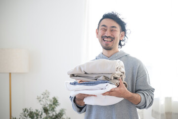 Asian (Japanese) man doing housework folding laundry
