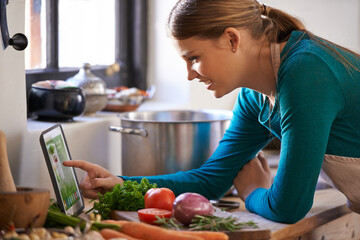 Woman, cooking and tablet with vegetables as recipe nutrition meal on kitchen counter, diet or connectivity. Female person, home and raw ingredients with internet or vegan eating, prepare or hungry